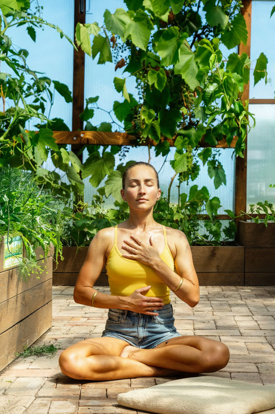Woman sitting in a greenroom doing breathwork